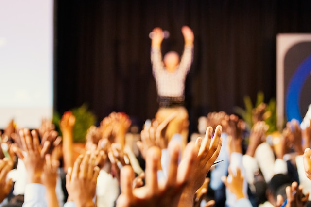 Many people at a conference with hands up in the air