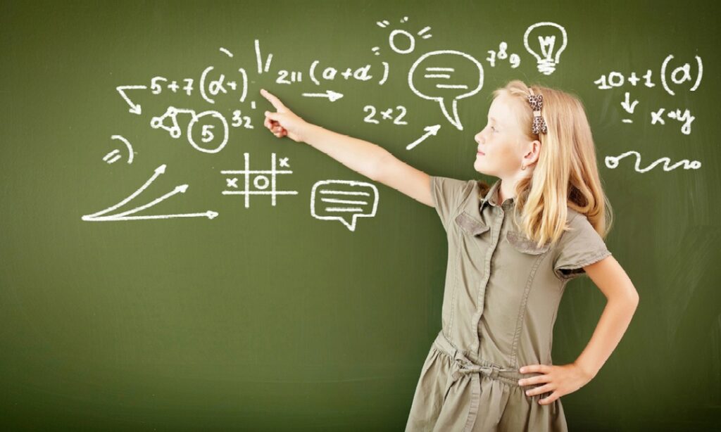 Girl in front of blackboard pointing to a complex formula written on it.