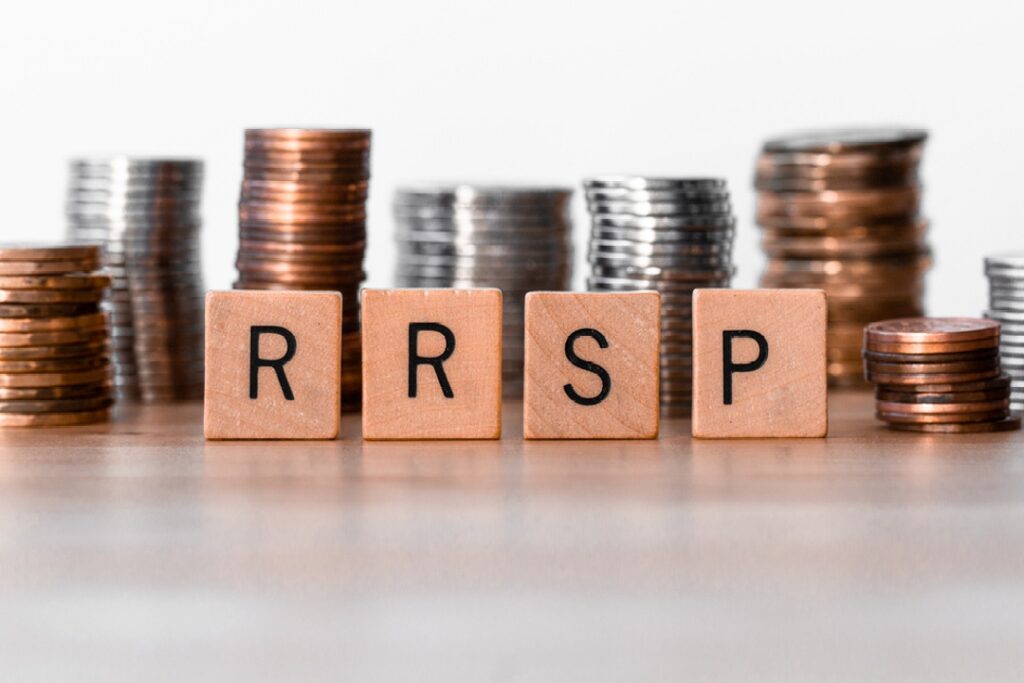 RRSP written on four wooden blocks standing in front of piles of coins
