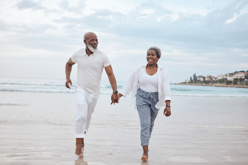 Older couple walking on a beach and smiling