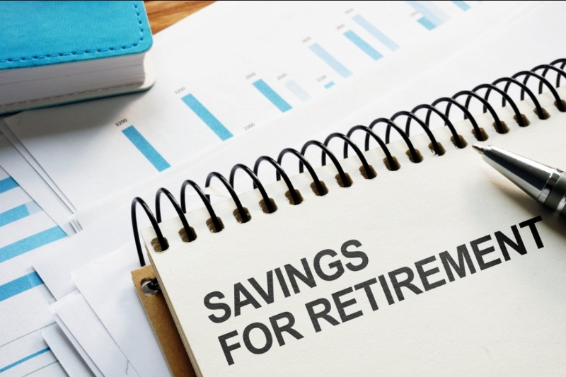 "Savings for Retirement" printed inside a notebook lying on top of some papers with blue highlights. 