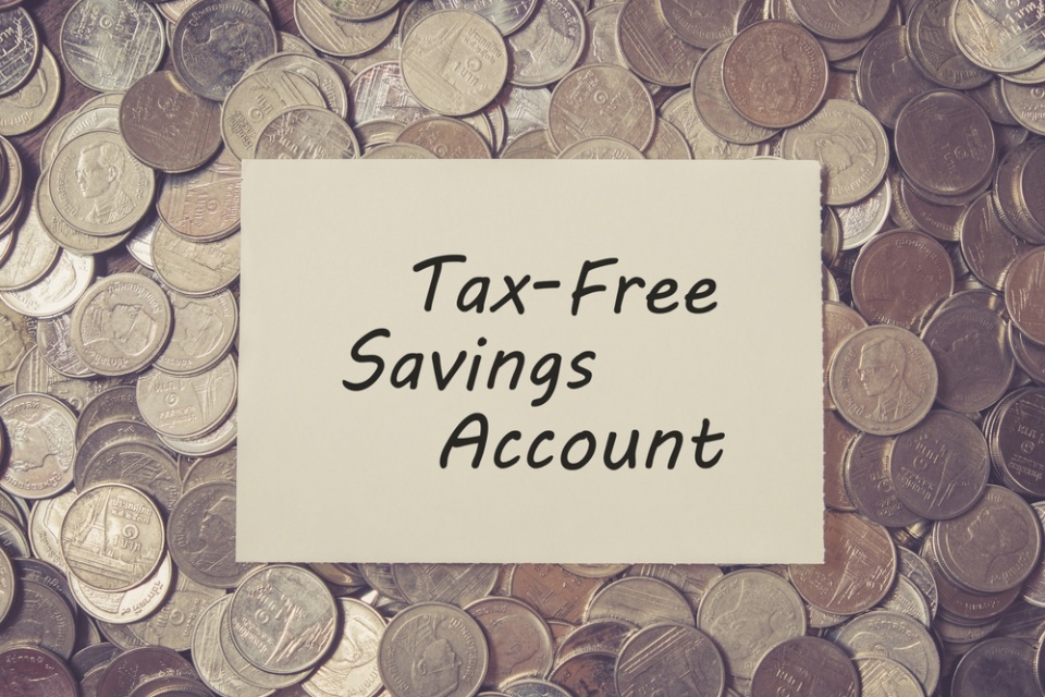 "Tax-Free Savings Account" is written in black marker on a yellow sticky placed on a bunch of spilled coins.
