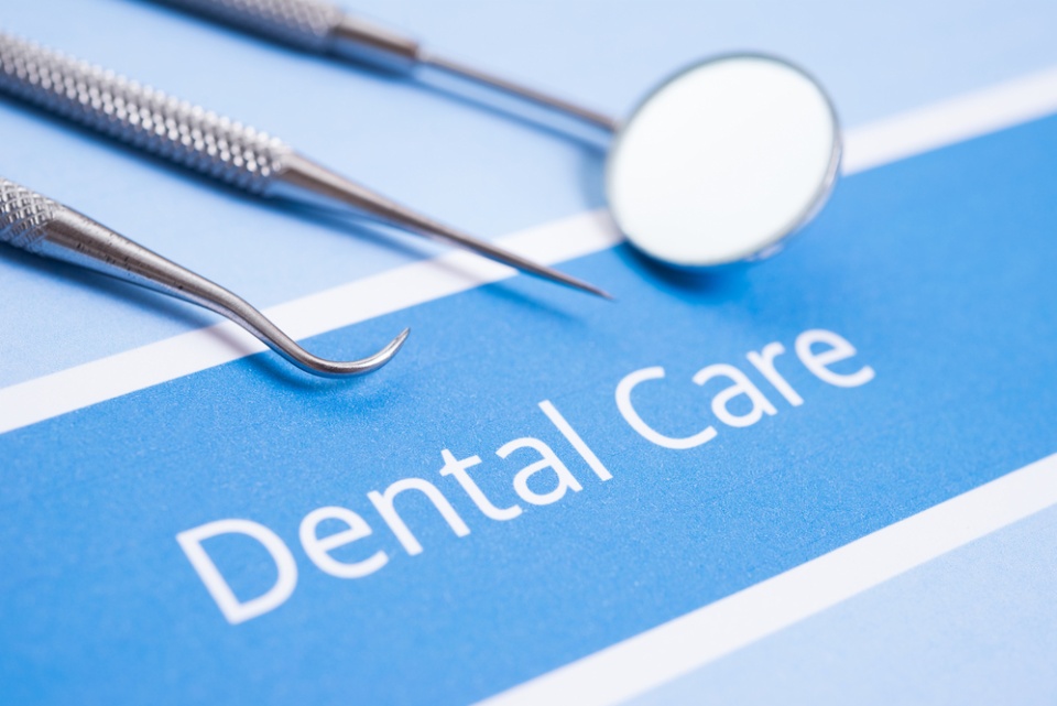 "Dental Care" typed in white on blue background next to three dental implements