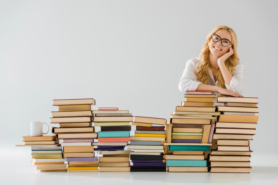 woman leaning on a big pile of books