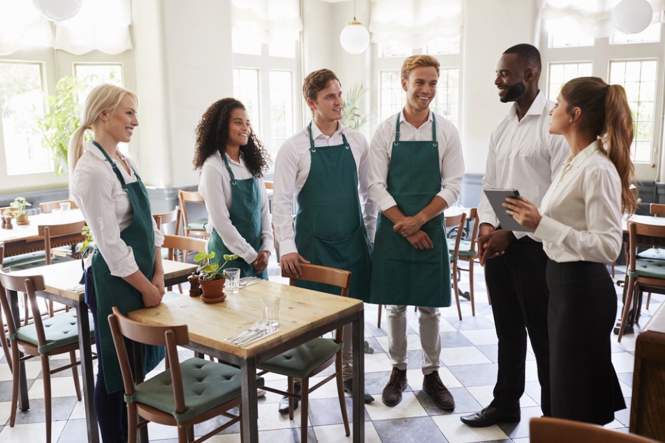 restaurant staff meeting - staff standing around table and discussing