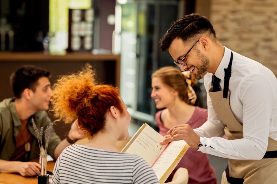 smiling waiter helping customer with menu selection